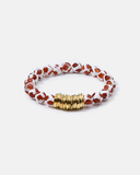 Beaded bracelet with red and white pattern and gold accents on a white background