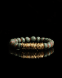 Bracelet with green and brown terracotta beads with gold spacers on a white background