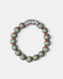 Bracelet with green and brown terracotta beads with silver spacers on a white background
