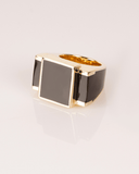 Gold ring with a black rectangular stone on a light gray background