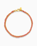 Pink and gold silk braided bracelet on a white background