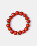 Red beaded bracelet with gold accents on a white background