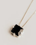 Necklace with a black geometric pendant on a light gray background