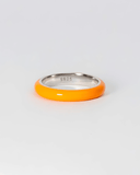 Silver ring with orange enamel band on a light gray background