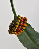 Beaded bracelets with multicolored beads on a green leaf against a light background
