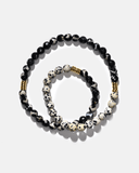 Beaded necklace with black, white, and gold beads on a light gray background