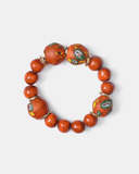 Bracelet with orange beads and decorative elements on a white background