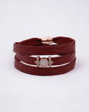 Burgundy leather wrap bracelet with a gold and rose gold clasp on a white background