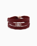 Burgundy leather wrap bracelet with a gold and rose gold clasp on a white background