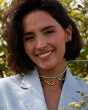 Woman wearing a sculpted metal necklace with a blue ribbon.