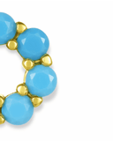 Close-up of a gold charm spacer with turquoise blue stones on a white background