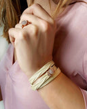 Close-up of a hand wearing a beige wrap leather bracelet with a rose gold clasp 
