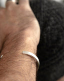 Close-up of a hand wearing a silver bangle bracelet