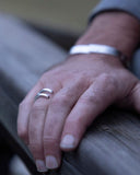 Close-up of a hand wearing a silver ring on a wooden surface