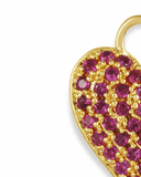 Close-up of a heart-shaped charm with pink stones and gold border on a white background