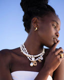 Close-up of a multi-strand pearl necklace with gold charms on a white background