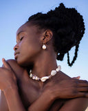 Close-up of a necklace with white stones, pearls, and gold clasp on a light gray background