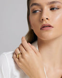 Close-up of a person wearing a gold ring on a plain background