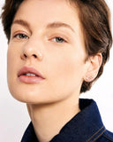 Close-up of a person wearing a small stud earring on a plain background