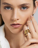 Close-up of a person wearing a stack of gold rings on a neutral background