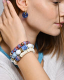 Close-up of a person wearing colorful beaded bracelets and blue earrings.