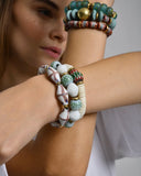 Close-up of a person wearing multiple colorful beaded bracelets on a plain background