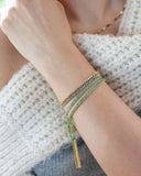 Close-up of a wrist with green and blue silk tassel bracelets