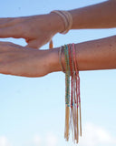 Close-up of a person's wrist with multiple colorful silk tassel bracelets