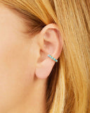 Close-up of an ear wearing a turquoise ear cuff with blonde hair.