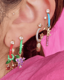 Close-up of an ear with multiple colorful earrings and charms 
