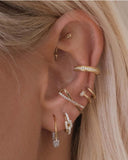 Close-up of an ear with multiple gold earrings 