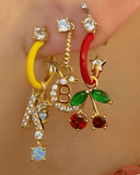 Close-up of colorful earrings with gold enamel hoops and charms