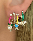Close-up of colorful hoop earrings with charms on an ear 