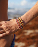 Colorful silk bracelets on a wrist with a blurred beach background