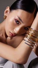 Woman wearing a stack of gold and silver bangle bracelets