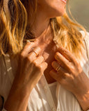 Close-up of a woman wearing gold rings on a blurred natural background