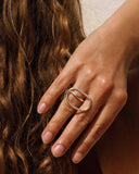 Hand wearing a gold ring with a unique design, close-up shot.