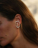Close-up of a person wearing a silver earring with a blurred background