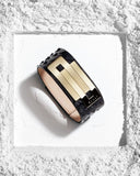 Gold and black leather bracelet on a textured white surface