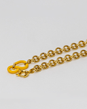 Gold chain necklace with a yellow clasp on a light gray background