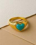 Gold ring with a turquoise heart on a beige background