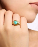 Gold ring with a turquoise heart stone on a hand