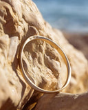 Gold bracelet on a textured rock with a blurred natural background