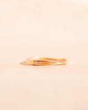 Gold ring with a small diamond on a beige background