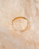 Gold ring with small diamonds on a textured beige surface