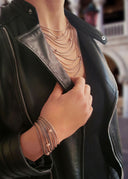 Woman wearing multiple gold necklaces and bracelets on a blurred background