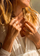 Close-up of a woman wearing gold rings on a blurred natural background