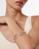 Mini silver bangle bracelet on a wrist with a neutral background