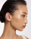 Model wearing a silver ear cuff with three intertwined bands on a white background
