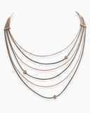 Multi-layered necklace with rose gold and black chains on a white background